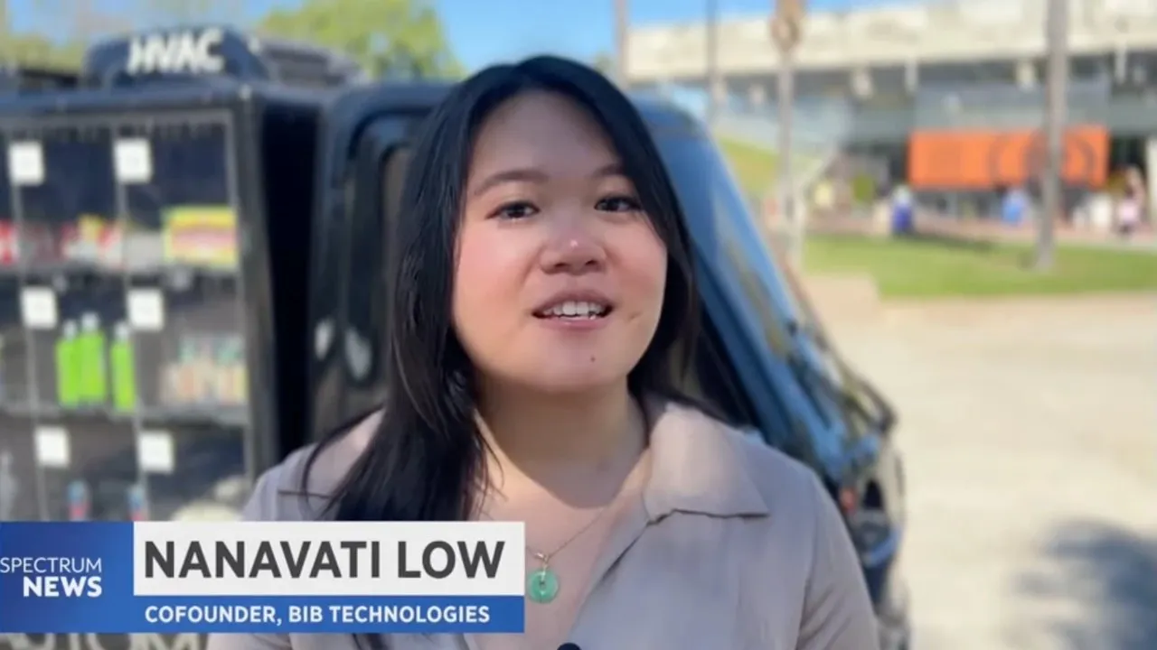 Nanavati Low on Spectrum News 1 in front of the Automato’s wall of lockers, captioned “Nanavati Low, Cofounder, BIB Technologies”.